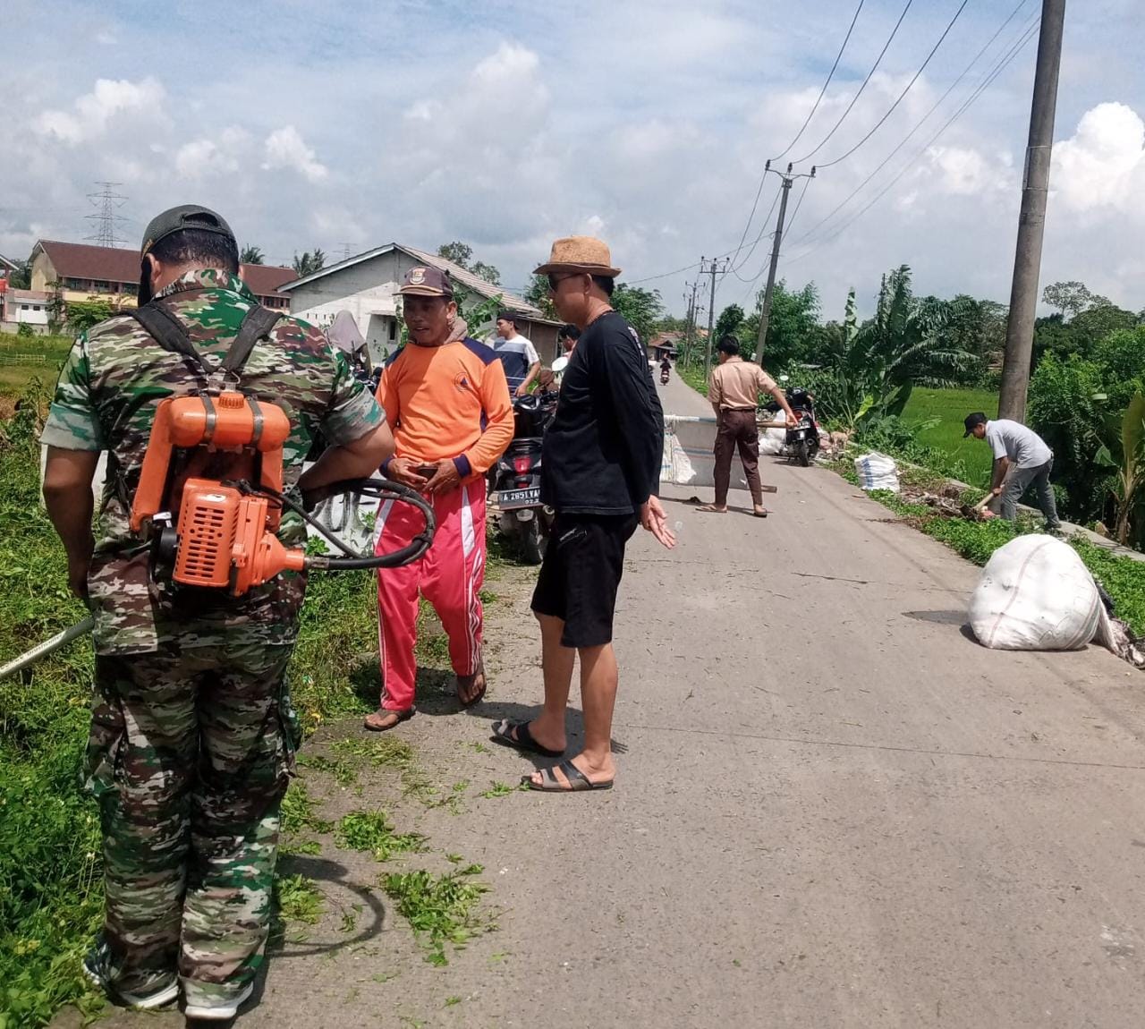 Peduli Lingkungan, Babinsa Serma H Sugandi Bersama Elemen Masyarakat Bersihkan Sampah di Pinggir Jalan   